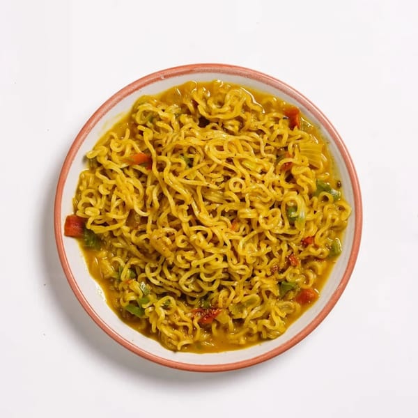 A bowl of Indian-style instant noodles with vegetables in a savory broth.