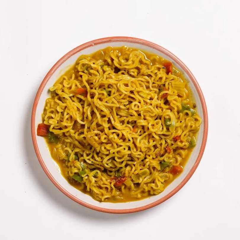 A bowl of Indian-style instant noodles with vegetables in a savory broth.